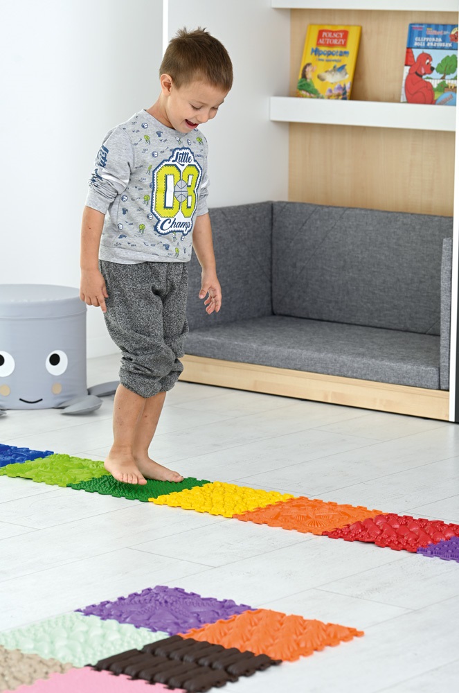 Ćwiczenia integracji sensorycznej, dziecko chodzące po matach masujących