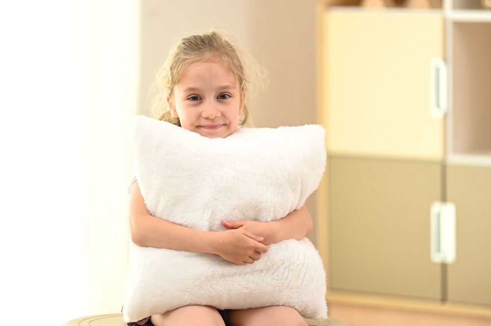 Dziewczynka przytula się do poduszki wibrującej.